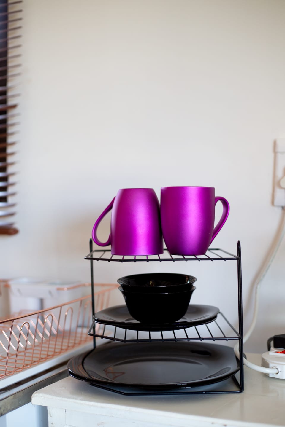 A simple kitchenette setup with bright mugs and black crockery, adding a playful touch to the cabin stay.
